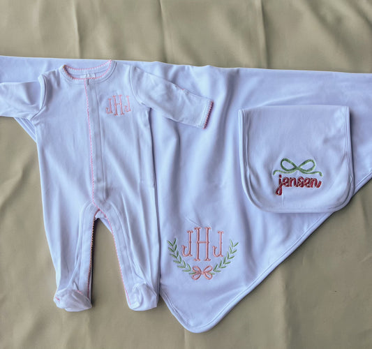 White baby outfit with embroidered designs on a beige surface